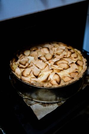 Home baking apple Tsvetaevsky aspic open pie in the oven, close-up. Baking concept. Family dinner. Dark background.の写真素材