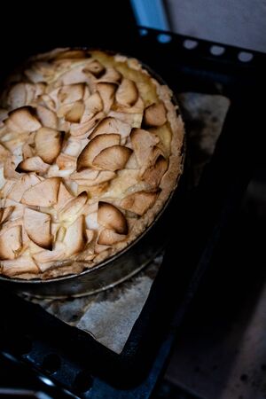 Home baking apple Tsvetaevsky aspic open pie in the oven, close-up. Baking concept. Family dinner. Dark background.の写真素材