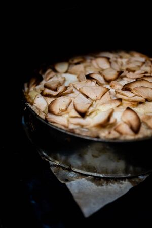 Home baking apple Tsvetaevsky aspic open pie in the oven, close-up. Baking concept. Family dinner. Dark background.の写真素材