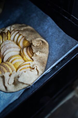 Raw apple galette - pie on white baking parchment. Copy space, flat layの写真素材
