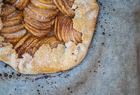 Apple galette - pie on baking parchment and dark background. Copy space, flat layの写真素材