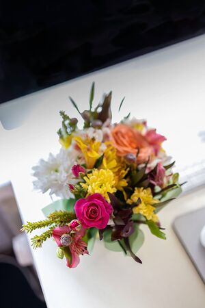 A stylish bouquet with fresh spring flowers is on the desktop near the computer, keyboard and mouse. Blur, selective focus.の写真素材