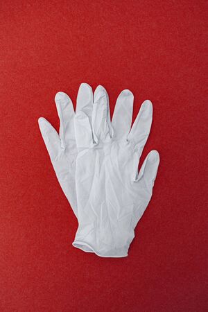 Medical surgical gloves on a red background. World pandemic coronavirus. Health and prevention of influenza and an infectious outbreak. New Coronavirus 2019-nCoVの写真素材