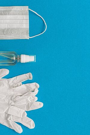 protective medical mask, gloves, alcohol disinfector on a blue background. Concept, fight, prevention, quarantine against coronavirus flu infection. View from above. Flat lay.の写真素材