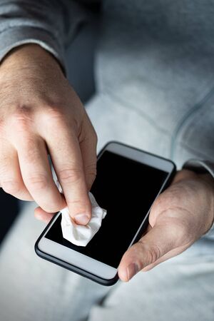 Man cleaning smartphone screen with alcohol or disinfectant. The concept of cleaning a dirty phone screen to prevent diseases from infectious bacteria. coronavirus covid 19.の写真素材