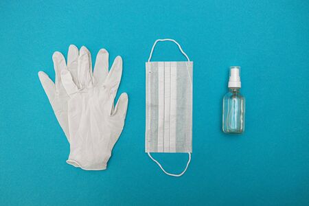 protective medical mask, gloves, alcohol disinfector on a blue background. Concept, fight, prevention, quarantine against coronavirus flu infection. View from above. Flat lay.の写真素材