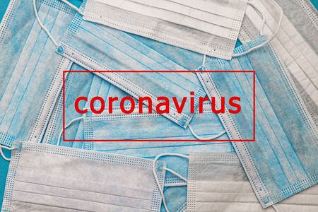 Medical disposable face masks on a blue background with the inscription stop coronavirus covid 19. World pandemic coronavirus. Stop the pandemic. Health and prevention of influenza and an infectious outbreak. Quarantine. New 2019 nCoV virus.の写真素材