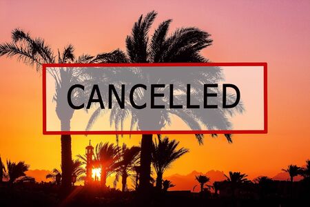 Crisis in the tourism industry due to outbreaks of coronavirus. Stopped traveling, red stamp text. Canceled text on a tropical beach with palm trees. Cancellation of a cruise due to the Covid-19 pandemic.の写真素材