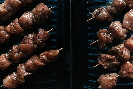 Skewers on skewers from raw meat of pork and beef, chicken cooked on a home electric grill. Top view. Selective focus. Blurの写真素材