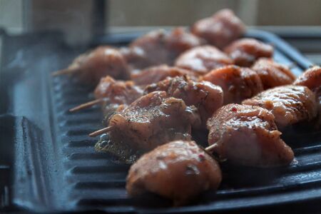 Skewers on skewers from raw meat of pork and beef, chicken cooked on a home electric grill. Top view. Selective focus. Blurの写真素材