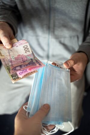Speculation on medical masks. people illegally sell masks very expensive because they are in short supply. hands pass masks for money, Ukrainian hryvnia. World pandemic coronavirus Covid-19, Pneumonia, medicineの写真素材