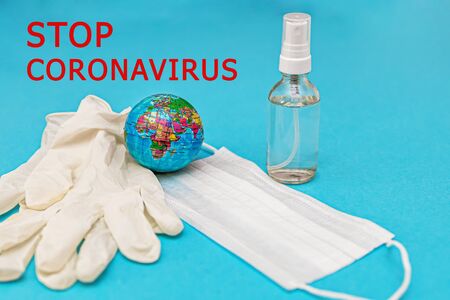 protective medical mask, gloves, alcohol disinfector, earth on a blue background. Concept, fight, prevention, quarantine against coronavirus flu infection. View from above. Flat lay.の写真素材