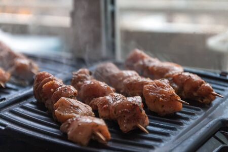 Skewers on skewers from raw meat of pork and beef, chicken cooked on a home electric grill. Top view. Selective focus. Blurの写真素材