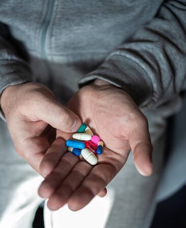 A man is holding various and multi-colored pills in his hands. Close-up. The concept of health protection and prevention of diseases with influenza and coronovirus. Relieve painの写真素材