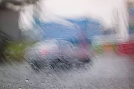 Traffic stands still, on a cold, wet day, shot through a windscreen, focusing on the rain droplets, tailights out of focus. View from car glass window. Conceptual bad weather background.の写真素材