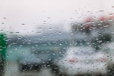 Traffic stands still, on a cold, wet day, shot through a windscreen, focusing on the rain droplets, tailights out of focus. View from car glass window. Conceptual bad weather backgroundの写真素材
