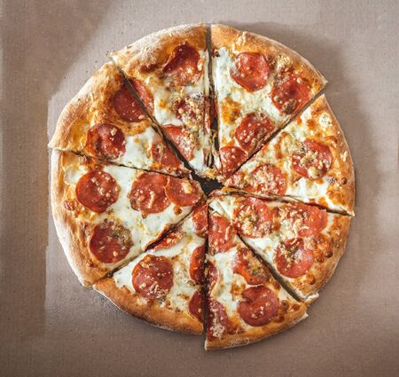 Pizza with pepperoni chopped into pieces in a courtesy box. Selective focus. View from above.の写真素材