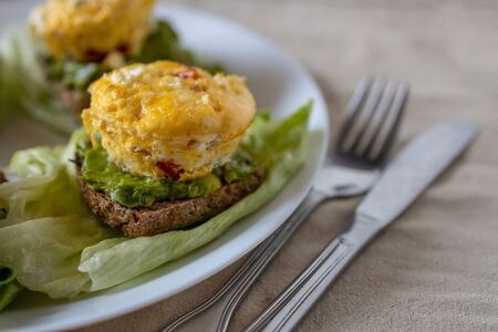 Omelet sandwich with vegetables on bread with avocado and lettuce, served on a white plate in a simple home-style. Flat lay, top view. Close-upの写真素材