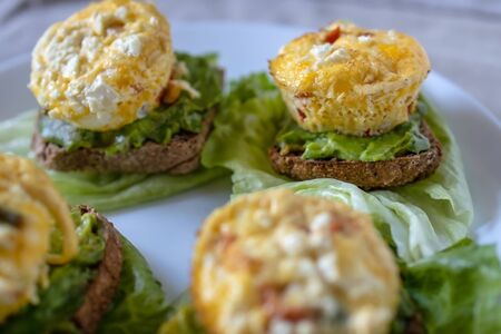 Omelet sandwich with vegetables on bread with avocado and lettuce, served on a white plate in a simple home-style. Flat lay, top view. Close-upの写真素材