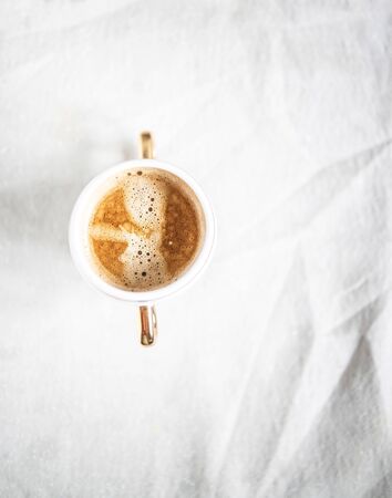 cup with cappuccino coffee on a light white retro sloppy fabric background. Copy space. Flat lay, top view. Minimalismの写真素材