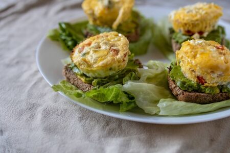Omelet sandwich with vegetables on bread with avocado and lettuce, served on a white plate in a simple home-style. Flat lay, top view. Close-upの写真素材