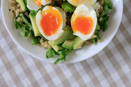 Salad with avocado, quinoa, arugula, soft-boiled eggs on a white plate. Close-up, top view. Healthy, healthy and healthy breakfast concept.の写真素材