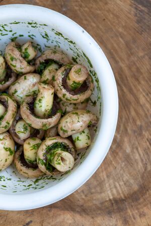in a bowl raw mushrooms champignons in a marinade with herbs, dill in a rustic natural form. View from aboveの写真素材