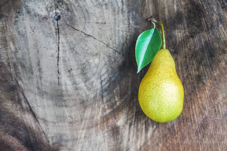 One juicy ripe pear with leaves lies on a wooden vintage dark background. Top view, copy space.の写真素材