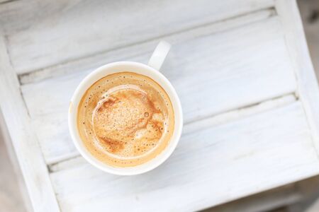 cappuccino coffee in a cup on a white wooden table. Top view, copy space.の写真素材