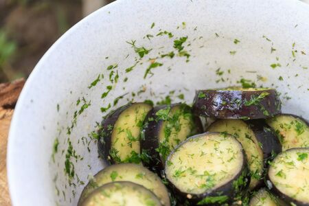 in a bowl, raw, struck eggplant in a marinade with herbs, dill in a rustic natural form. Preparation for grilling. View from above.の写真素材