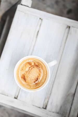 cappuccino coffee in a cup on a white wooden table. Top view, copy space.の写真素材
