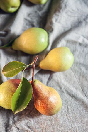 Ripe pears are scattered on a plain linen tablecloth. Simple village life and food. Top view, copy spaceの写真素材