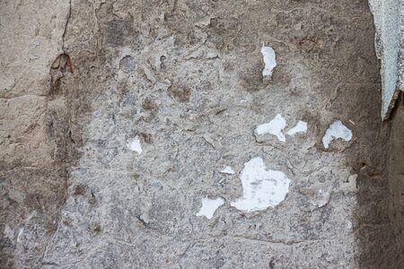 background of old cracked gray concrete through which red brick is visibleの写真素材