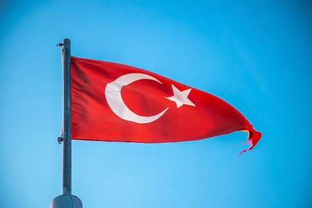 The Turkish flag flutters against a clear blue skyの写真素材