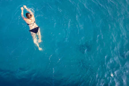 aerial top view happy young woman in black swimsuit swims in the Red Sea, Egypt, Sharm el Sheikh. Vacation and adventure. Blue water. Top view of a lazy girl resting in the sea-ocean. Copy spaceの写真素材