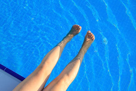 cropped young european woman kicks in the pool splashes water. Concept, carefree, summer, vacation. Copy space. View from aboveの写真素材