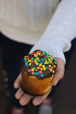 cropped female hands on the background of a white knitted sweater holding a traditional Easter cake.の写真素材