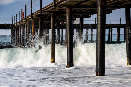 Turkey, Mediterranean Sea, on a pebble shore, waves break on the piles of a wooden pier.の写真素材