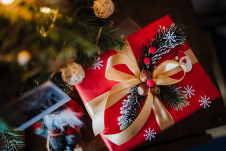 beautifully wrapped red gift box under the christmas tree, top view
