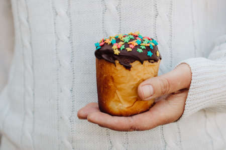 cropped female hands on the background of a white knitted sweater holding a traditional Easter cake.の写真素材