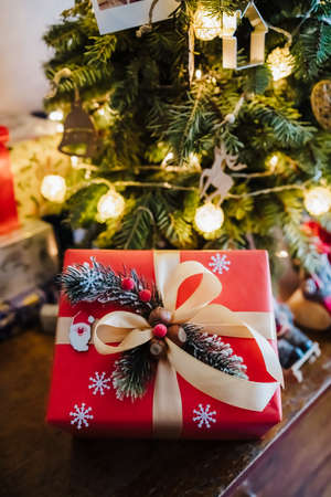 beautifully wrapped red gift box under the christmas tree, top view.