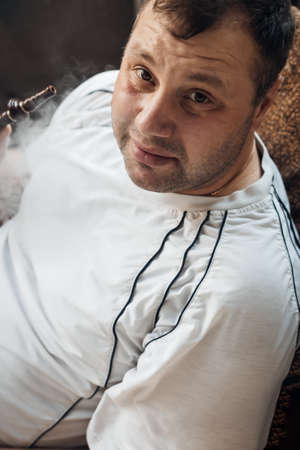 happy caucasian white young man smoking hookah and blowing smokeの写真素材