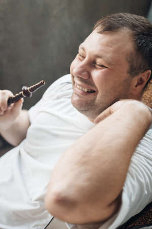 happy caucasian white young man smoking hookah and blowing smokeの写真素材
