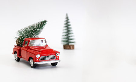 miniature red car in the back carries a Christmas tree on a white isolated background, top view. Save the space. Concept, festive Christmas mood, gift delivery. The trendの写真素材
