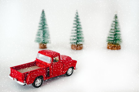 miniature red car in the back carries a Christmas tree on a white isolated background, top view. Save the space. Concept, festive Christmas mood, gift delivery. The trendの写真素材