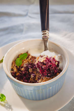 baked oat-blueberry crumble with mint in a white and blue plate on a rustic linen tablecloth. Save the space, top view. The concept of healthy proper nutrition for breakfast, vegetarianismの写真素材