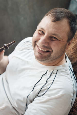 happy caucasian white young man smoking hookah and blowing smoke.の写真素材