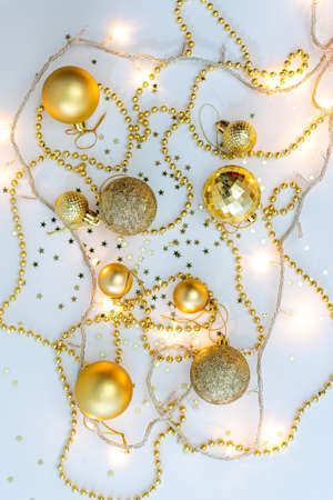 Christmas holidays composition, top view of gold Christmas decorations and garland with lights on a yellow background with copy space for text. Blur. Flat lay. Winter, postcard template.の写真素材