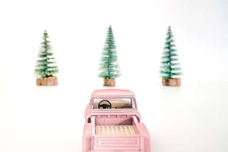 miniature pink car in the back carries a Christmas tree on a white isolated background, top view. Save the space. Concept, festive Christmas mood, gift delivery. The trendの写真素材