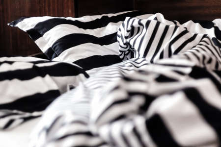 Unmade bed in black and white stripes. Close-upの写真素材